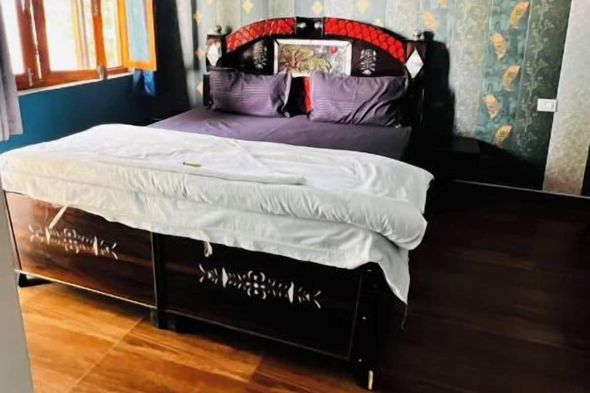 A bedroom with a bed, a window, and a wall with a decorative pattern.