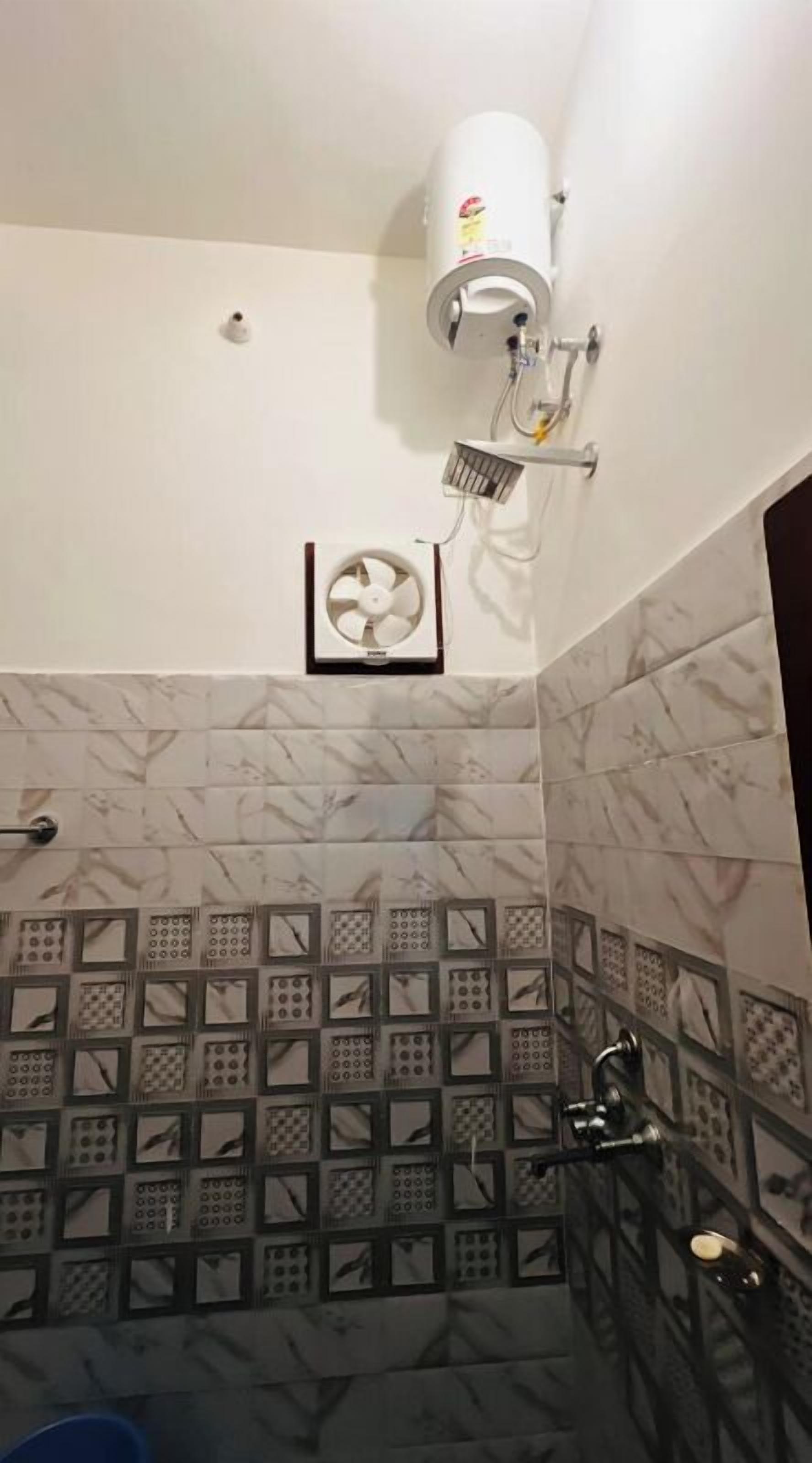 A bathroom with a white ceiling, a white wall-mounted fan, and a shower area with a black metal frame.