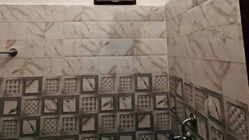 A bathroom with a white ceiling, a white wall-mounted fan, and a shower area with a black metal frame.