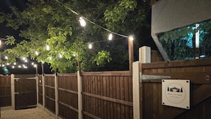 A wooden gate with a sign reading 'Machine Hideaway,' surrounded by a wooden fence and string lights.