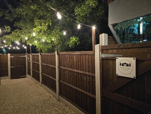 A wooden gate with a sign reading 'Machine Hideaway,' surrounded by a wooden fence and string lights. - Rural Romantic Cabin-Hot Tub & Outdoor Kitchen (Moira)