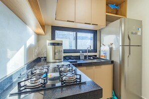 A modern kitchen with a gas stove, a coffee maker, and a refrigerator. - Cais Eco #212 - Apartment on the Sand by Carpediem (Ipojuca)