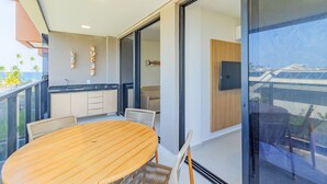A modern kitchen with a wooden table and chairs, a view of the ocean, and a balcony with a railing. - Cais Eco #212 - Apartment on the Sand by Carpediem (Ipojuca)