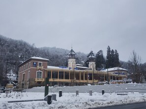 Ein mehrstöckiges Gebäude mit Balkon und schneebedecktem Dach.