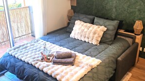 A bedroom with a large bed, a wooden nightstand, a wall-mounted shelf with books, and two framed artworks. - Ax-les-Thermes, cosy studio 4 pers and balcony : ski, hiking, thermal baths | All on foot (Savignac-les-Ormeaux)