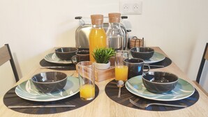 A wooden dining table set with black and green plates, bowls, glasses, and a juice pitcher. - Ax-les-Thermes, cosy studio 4 pers and balcony : ski, hiking, thermal baths | All on foot (Savignac-les-Ormeaux)
