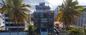 A modern building with a glass facade, surrounded by palm trees. - Breeze Residence #404 - Seafront by Carpediem (João Pessoa)