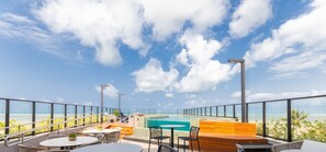 A rooftop pool area with a view of the ocean, outdoor seating, and a staircase leading to the pool. - Breeze Residence #404 - Seafront by Carpediem (João Pessoa)