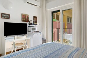 Une chambre avec un lit, un bureau avec une télévision, un four à micro-ondes et une chaise.