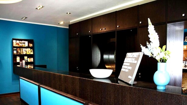 A reception desk with a dark wood finish, a white bowl, a sign, and a vase with white flowers. - Koblenz Valley Hotel Budget Double Room (Bendorf)