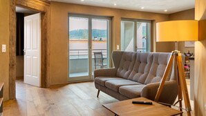 Una sala de estar con sofá, lámpara, un cuadro y un balcón con vistas.