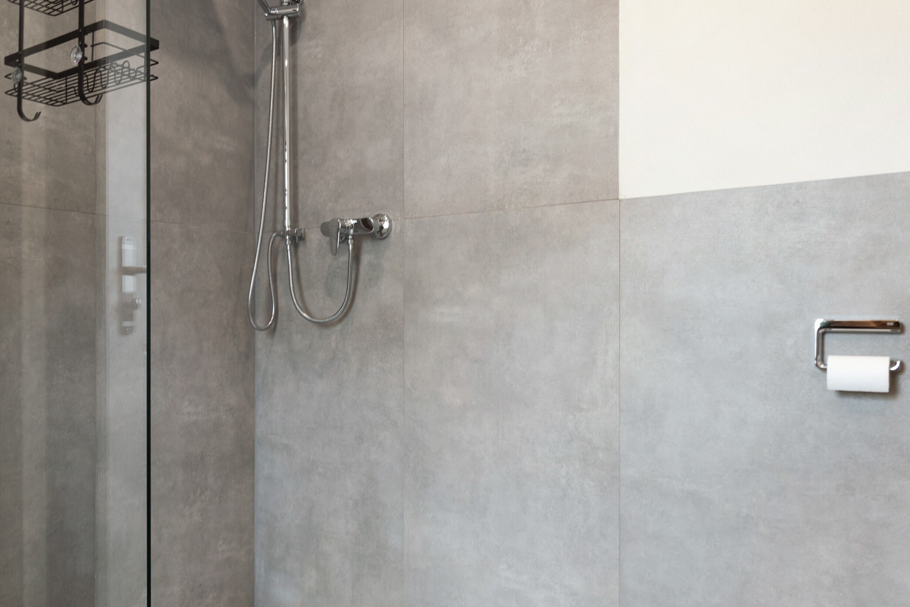 A shower area with a glass door, a metal showerhead, and a towel rack.
