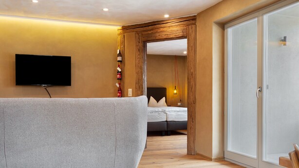 Una habitación de hotel moderna con televisión de pantalla plana en la pared, un sofá, una cama y un armario.