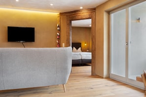 Una habitación de hotel moderna con televisión de pantalla plana en la pared, un sofá, una cama y un armario.