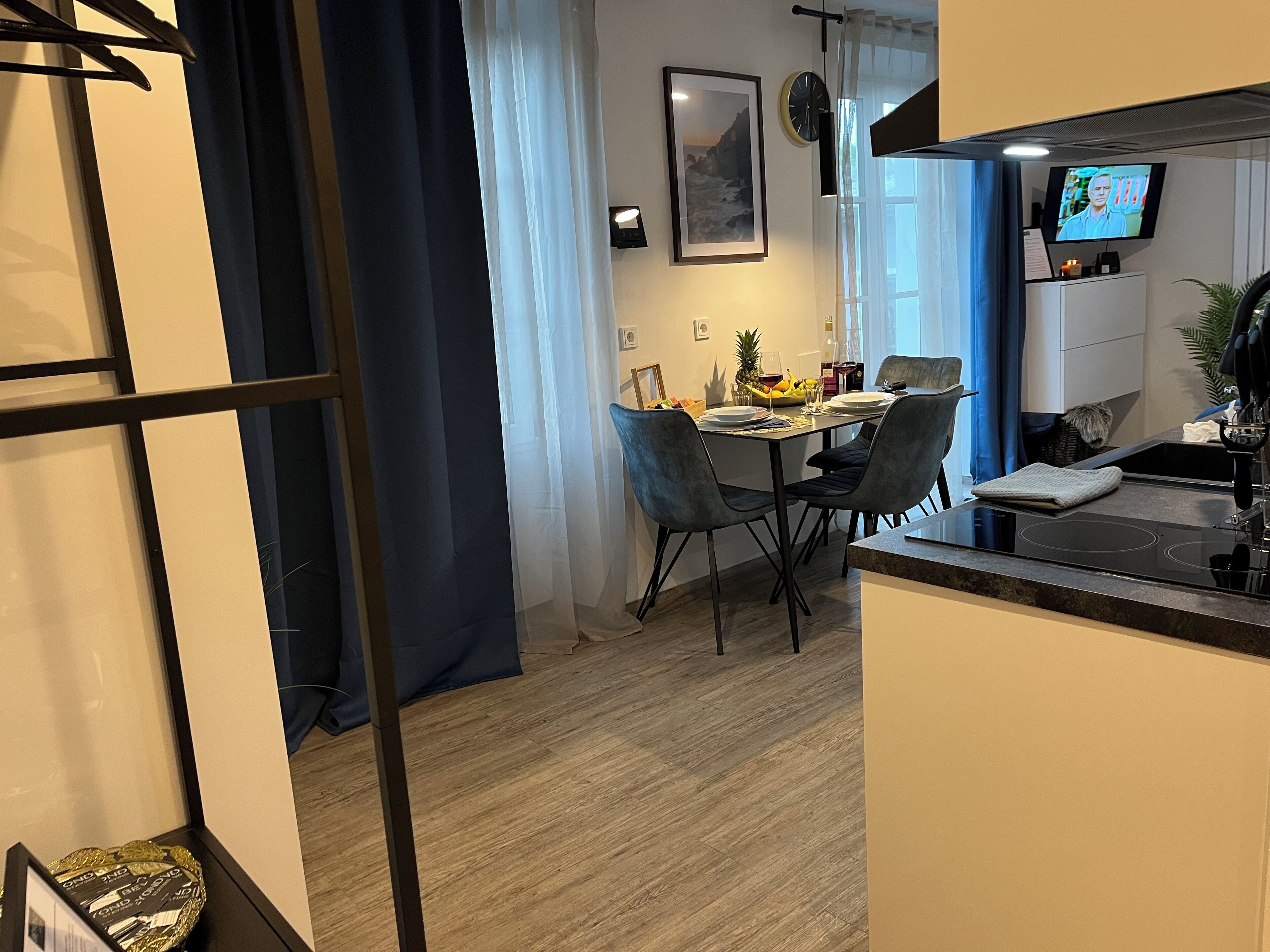 A modern kitchen with a dining area, featuring a black countertop, a built-in oven, and a dining table with chairs.