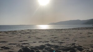 Une plage où l’on peut voir des empreintes de pas dans le sable, sous un ciel dégagé.