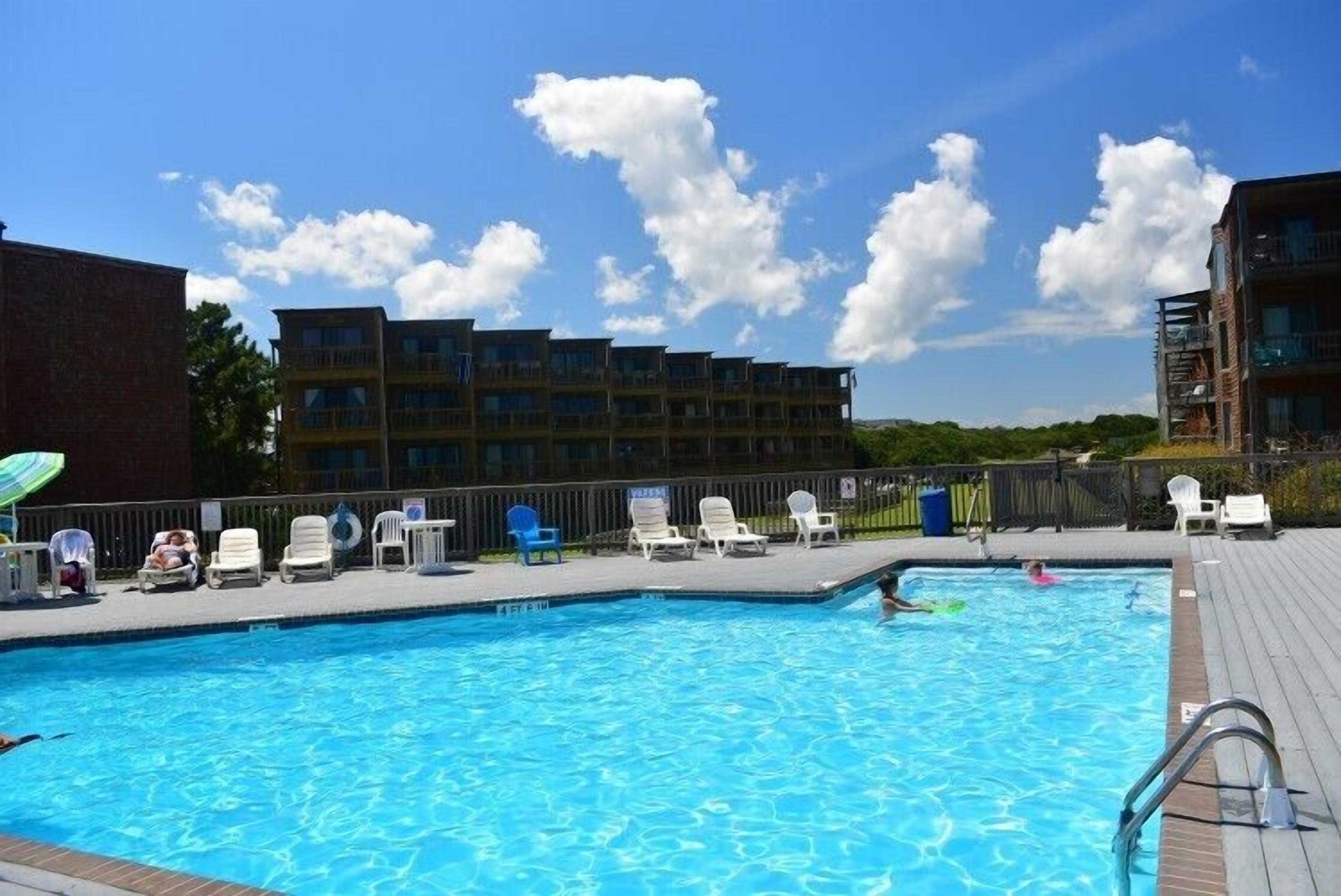 A swimming pool with lounge chairs and a view of multi-story buildings.