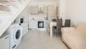 A compact apartment with a washing machine, kitchenette, dining area, and a bed. - Charming accommodation with pool in Viddalba (Viddalba)