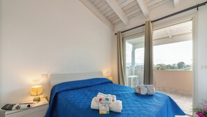 A hotel room with a bed, a nightstand, a lamp, a window with curtains, and a balcony. - Charming accommodation with pool in Viddalba (Viddalba)