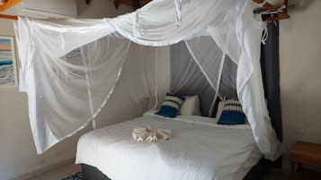 Una cama con dosel blanco y una alfombra estampada azul.