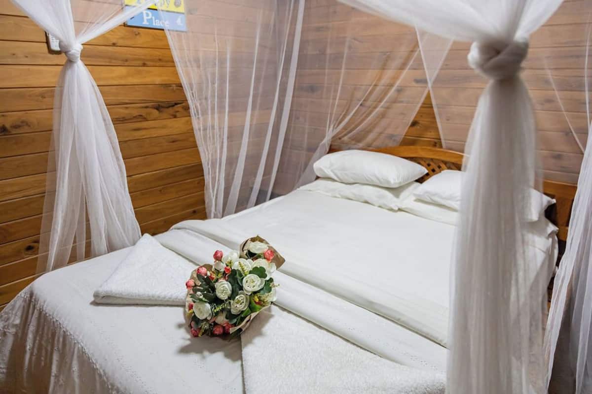 Un lit à baldaquin blanc et un bouquet de fleurs.