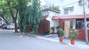 Eine Wohnstraße mit einem Haus, das ein rotes Ziegeldach, ein befestigtes Eingangstor und Kübelpflanzen hat.
