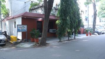 Un edificio pequeño con techo rojo, un letrero y plantas en macetas.