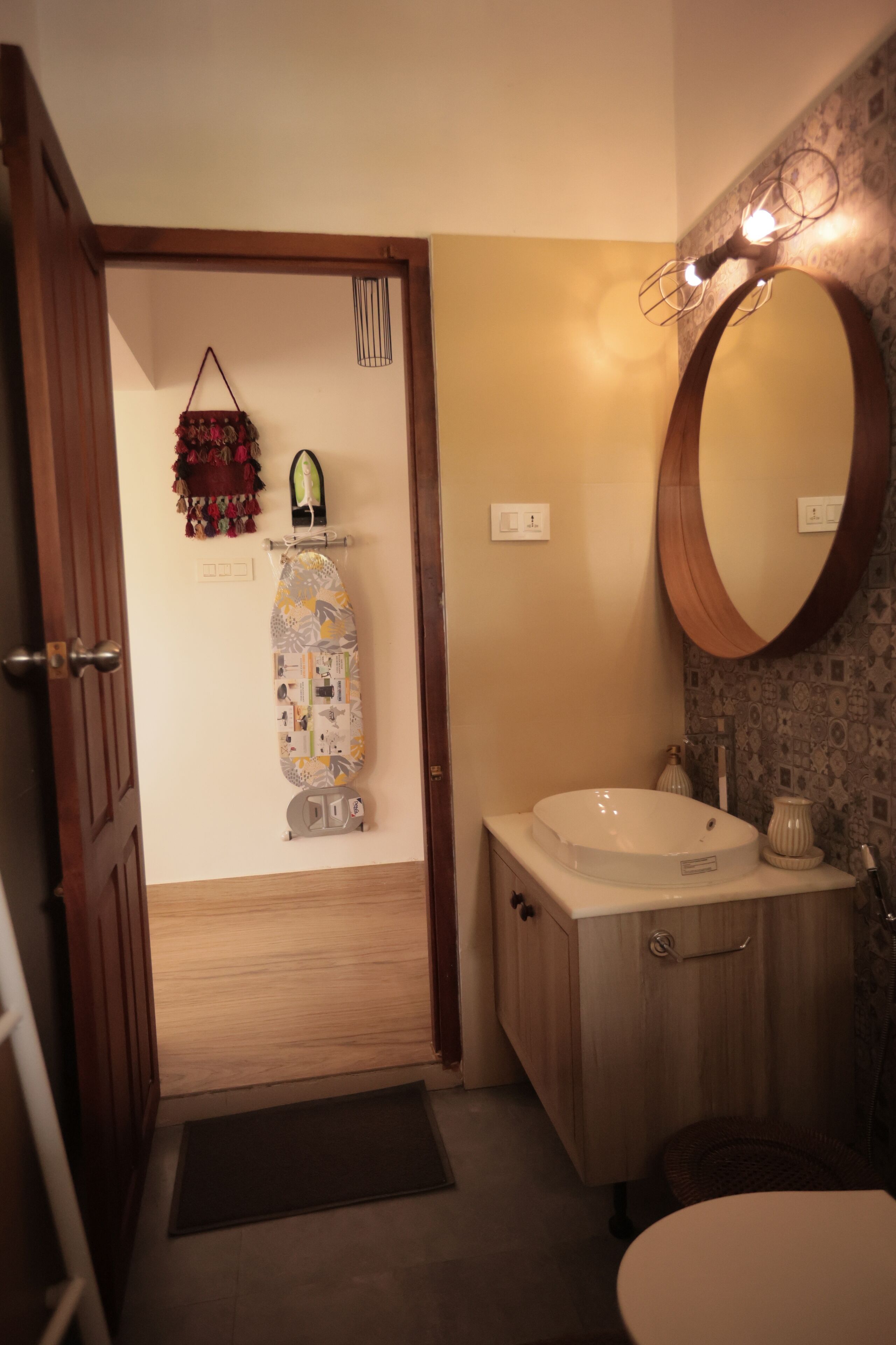 A bathroom with a wooden door, a white sink, a mirror, and a patterned wall.