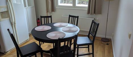 A dining area with a round table, four chairs, and a window with curtains.