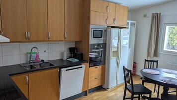 A modern kitchen with wooden cabinets, a built-in oven, a microwave, and a refrigerator.