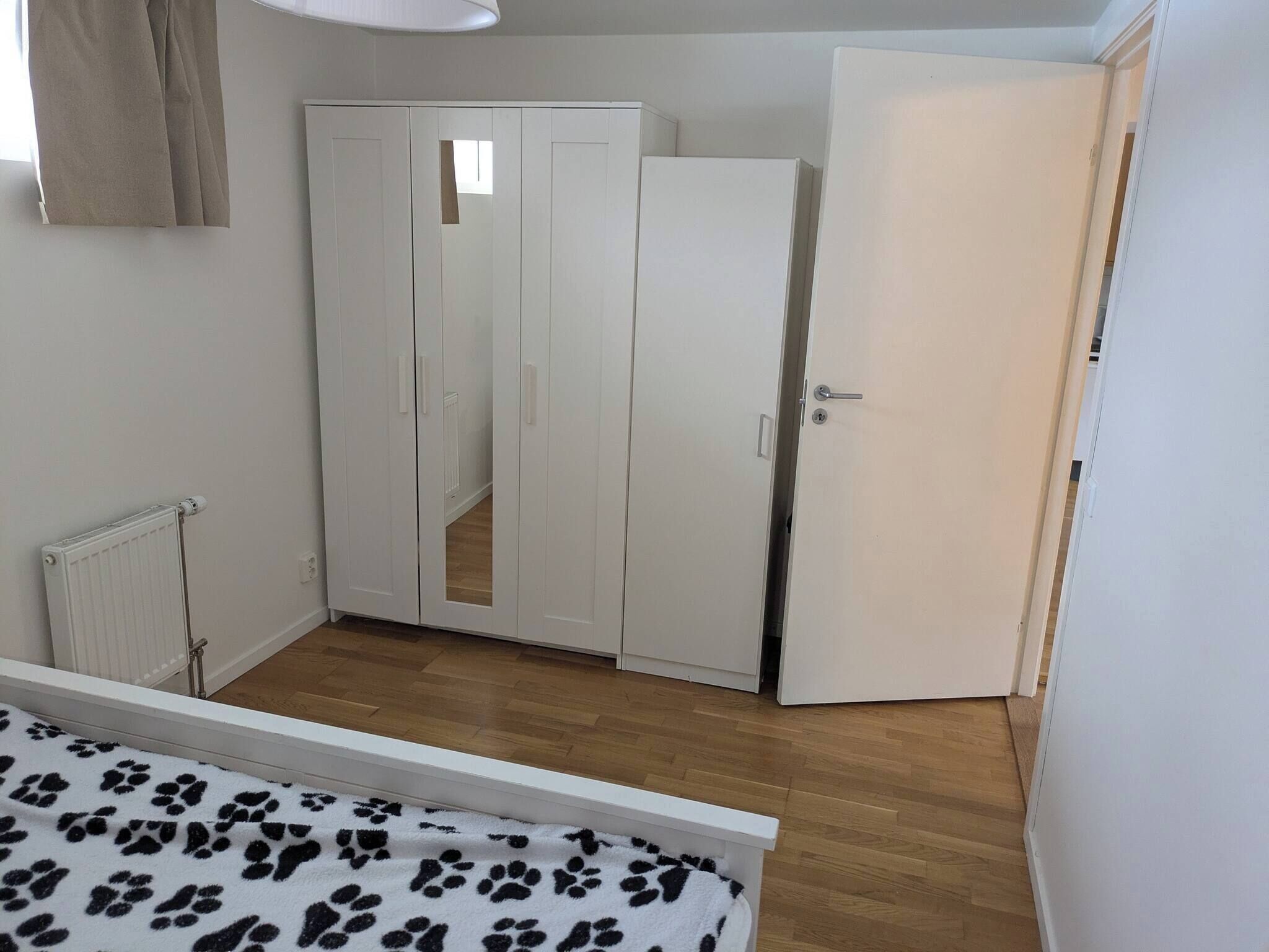 A bedroom with a wardrobe, a radiator, and a door.