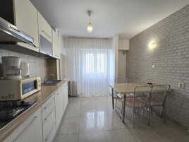 Una cocina moderna con estufa, microondas y comedor con mesa y sillas.