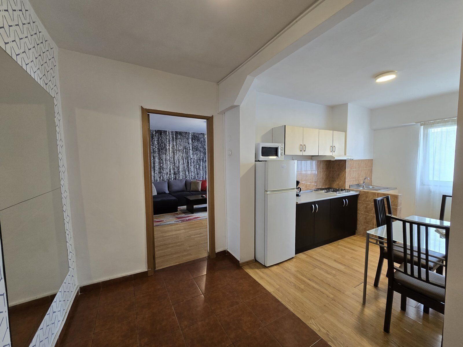A compact living space with a kitchenette, a dining area, and a living room with a sofa and a coffee table.