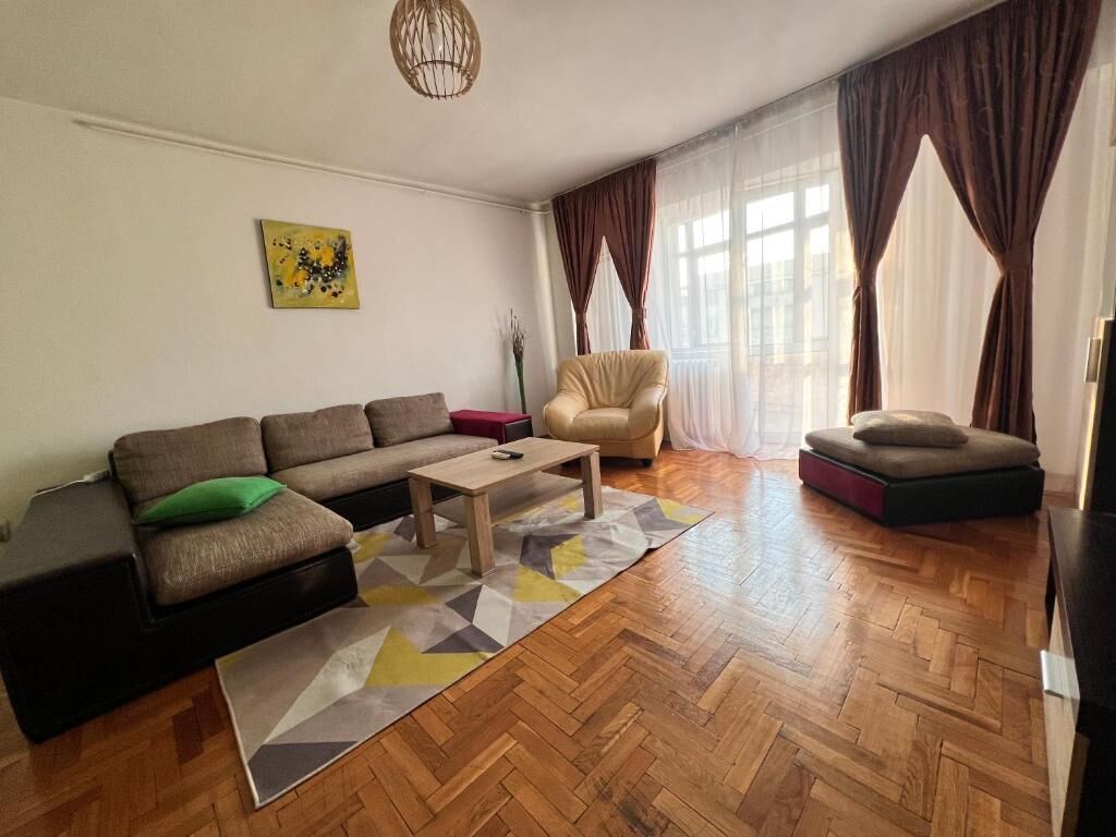 Un salon comprenant un canapé, un fauteuil et un pouf, une table basse et un tapis.