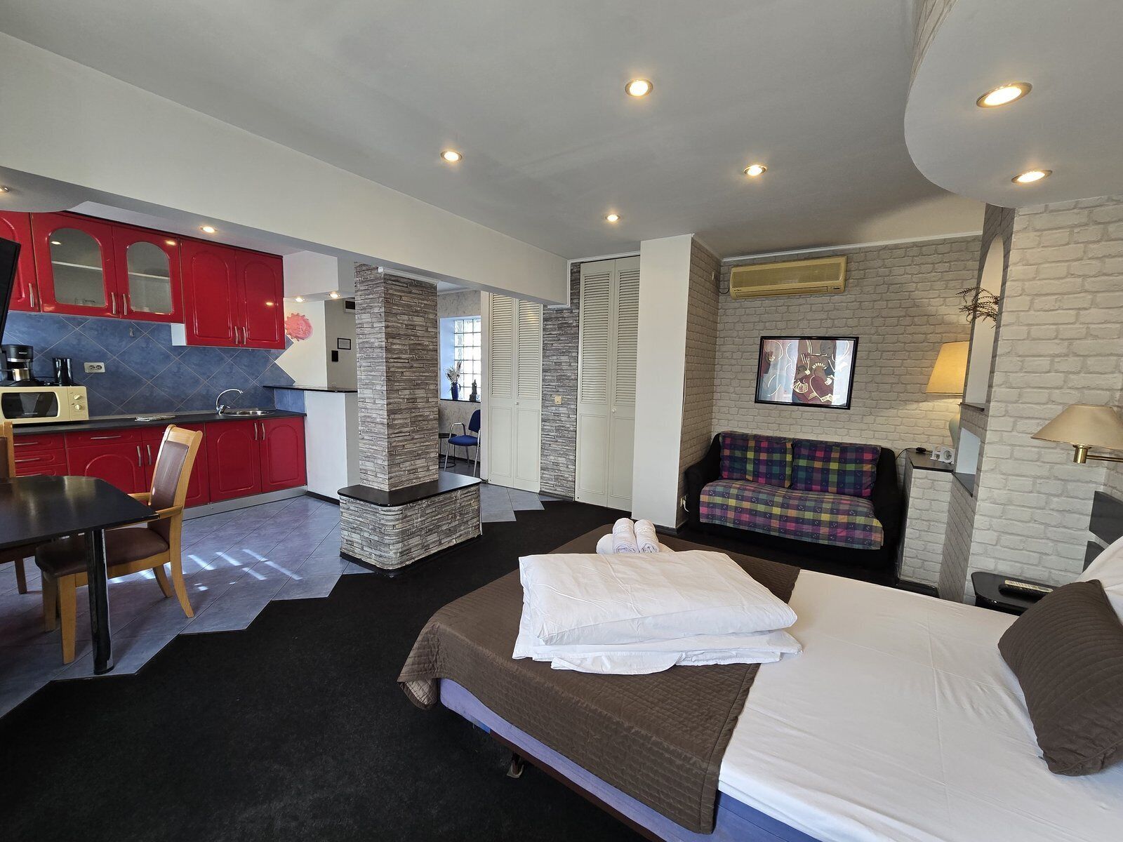 Une chambre d’hôtel de taille réduite comprenant un lit, un canapé, une table à manger et un coin cuisine.