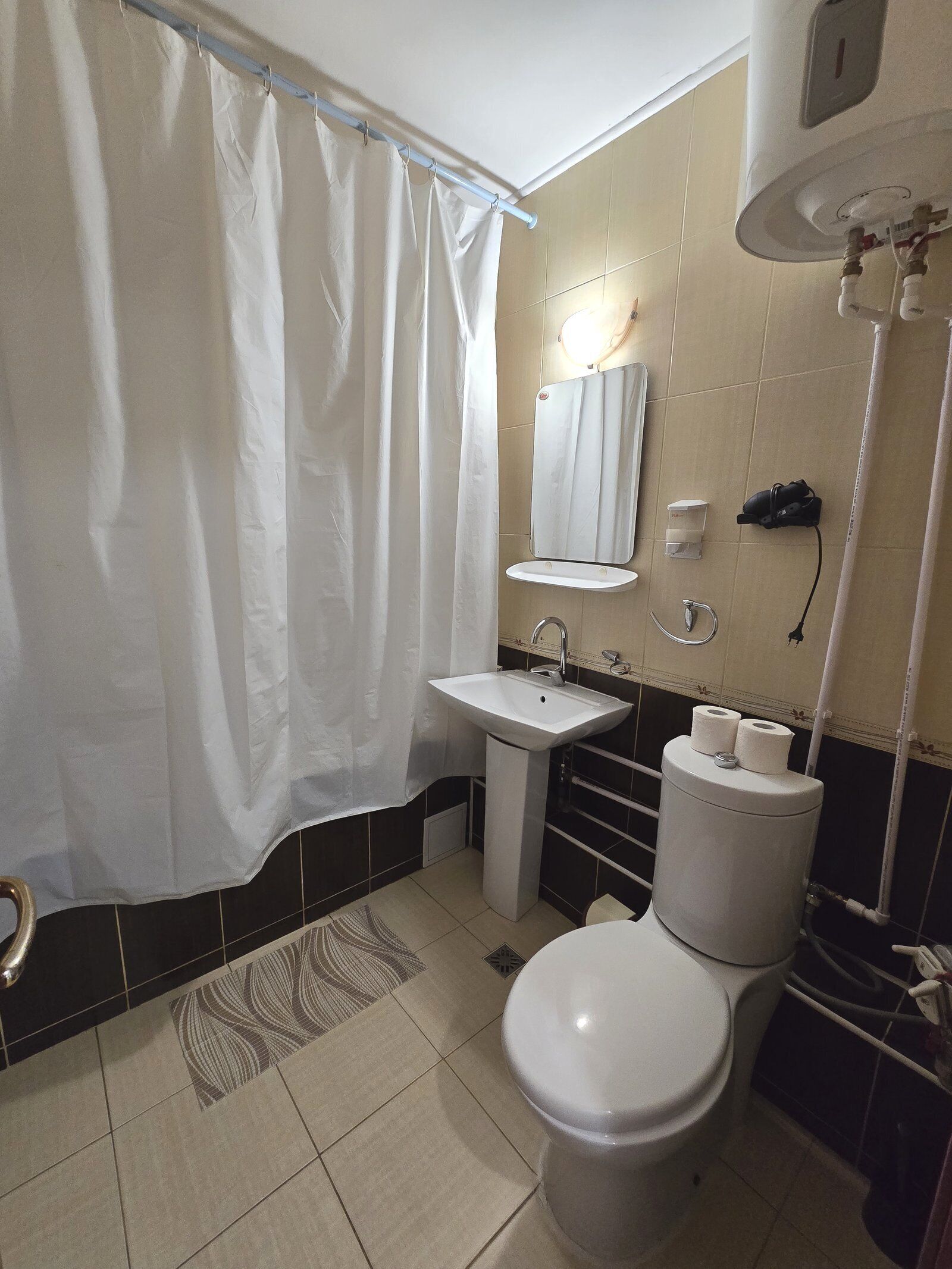 A bathroom with a shower curtain, sink, mirror, toilet, and a towel rack.