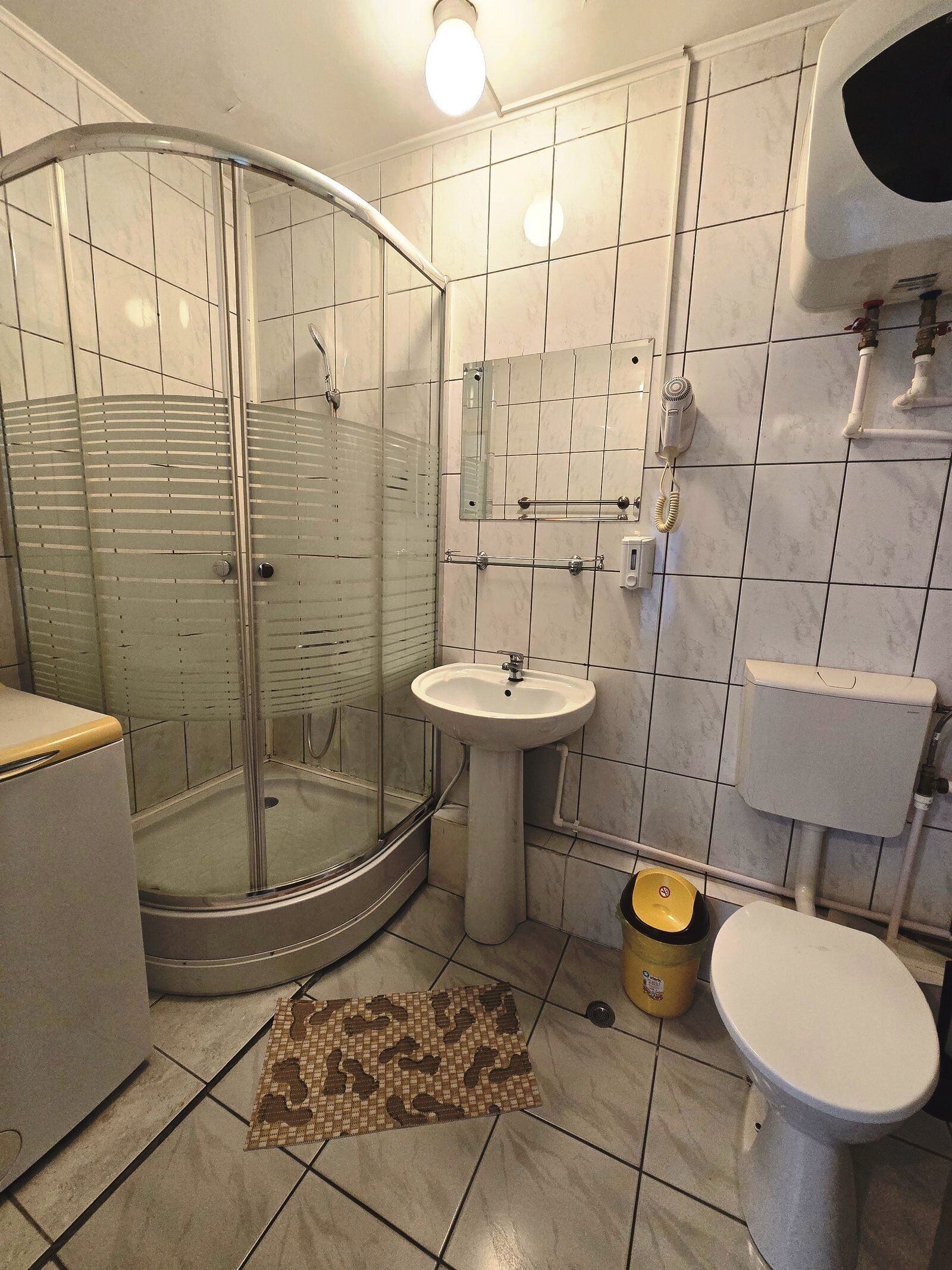 Ein Badezimmer mit Duschkabine, Waschbecken, Toilette und Spiegel.