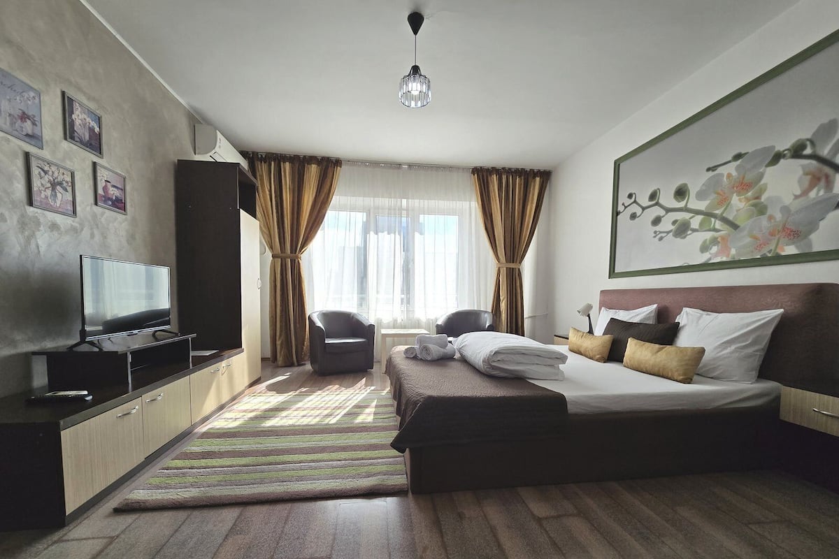 Una habitación de hotel con cama, televisor, escritorio y silla.
