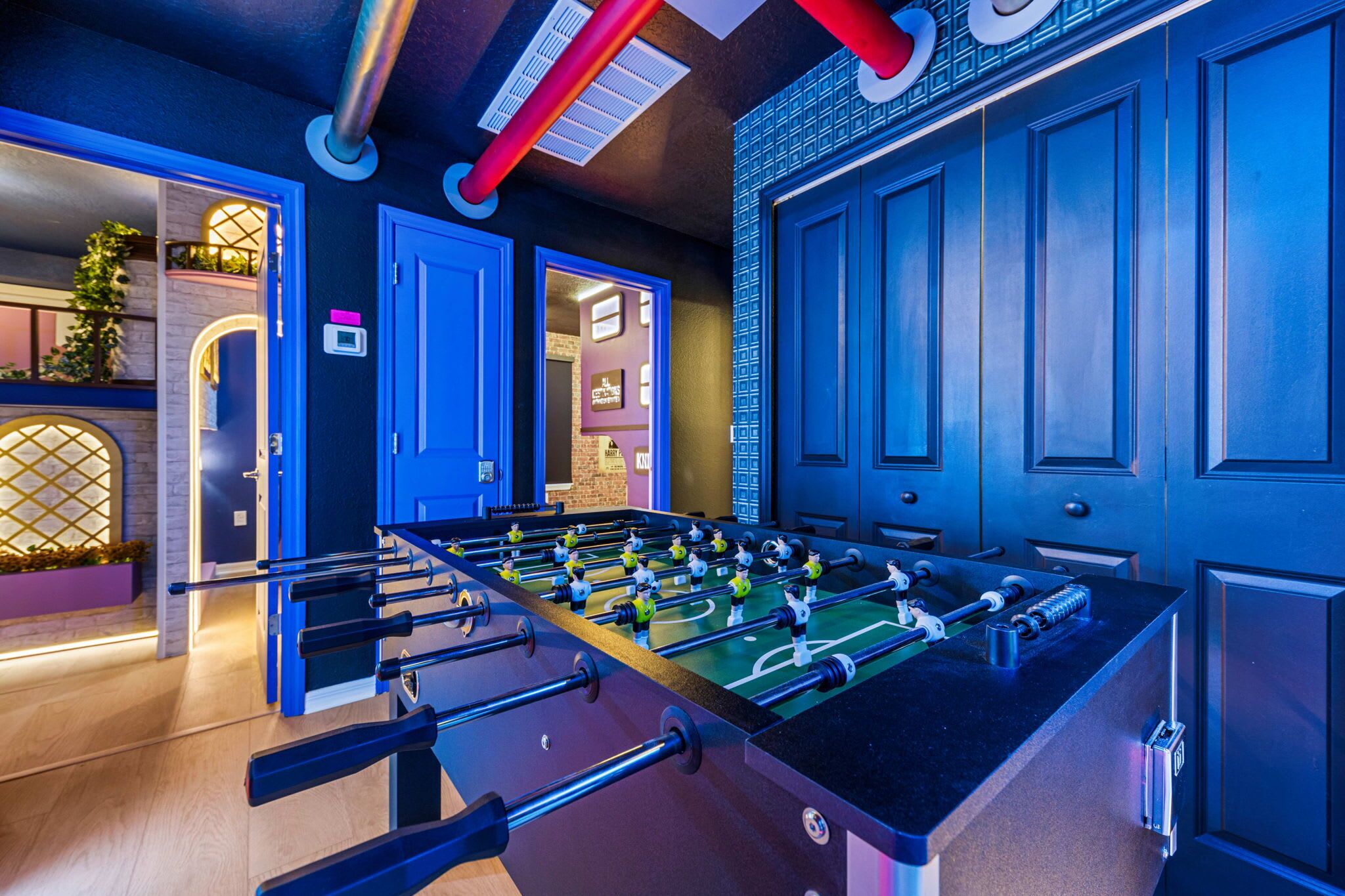 Una habitación con mesa de fútbol de mesa, una puerta con picaporte azul y una pared con diseño decorativo.