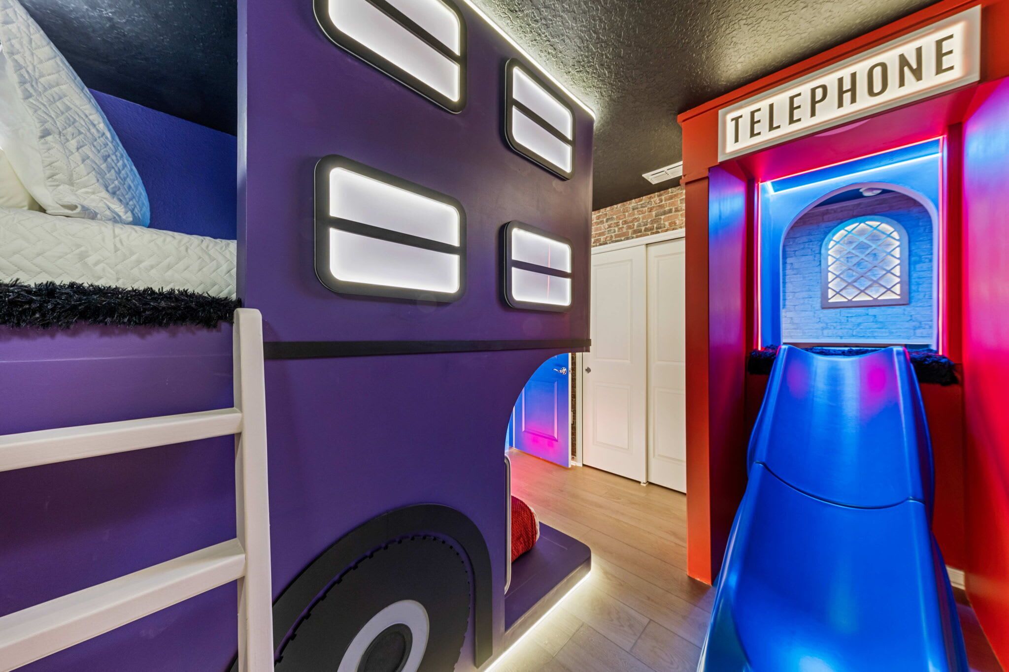 A children's play area with a slide, a bed, and a telephone-themed wall.