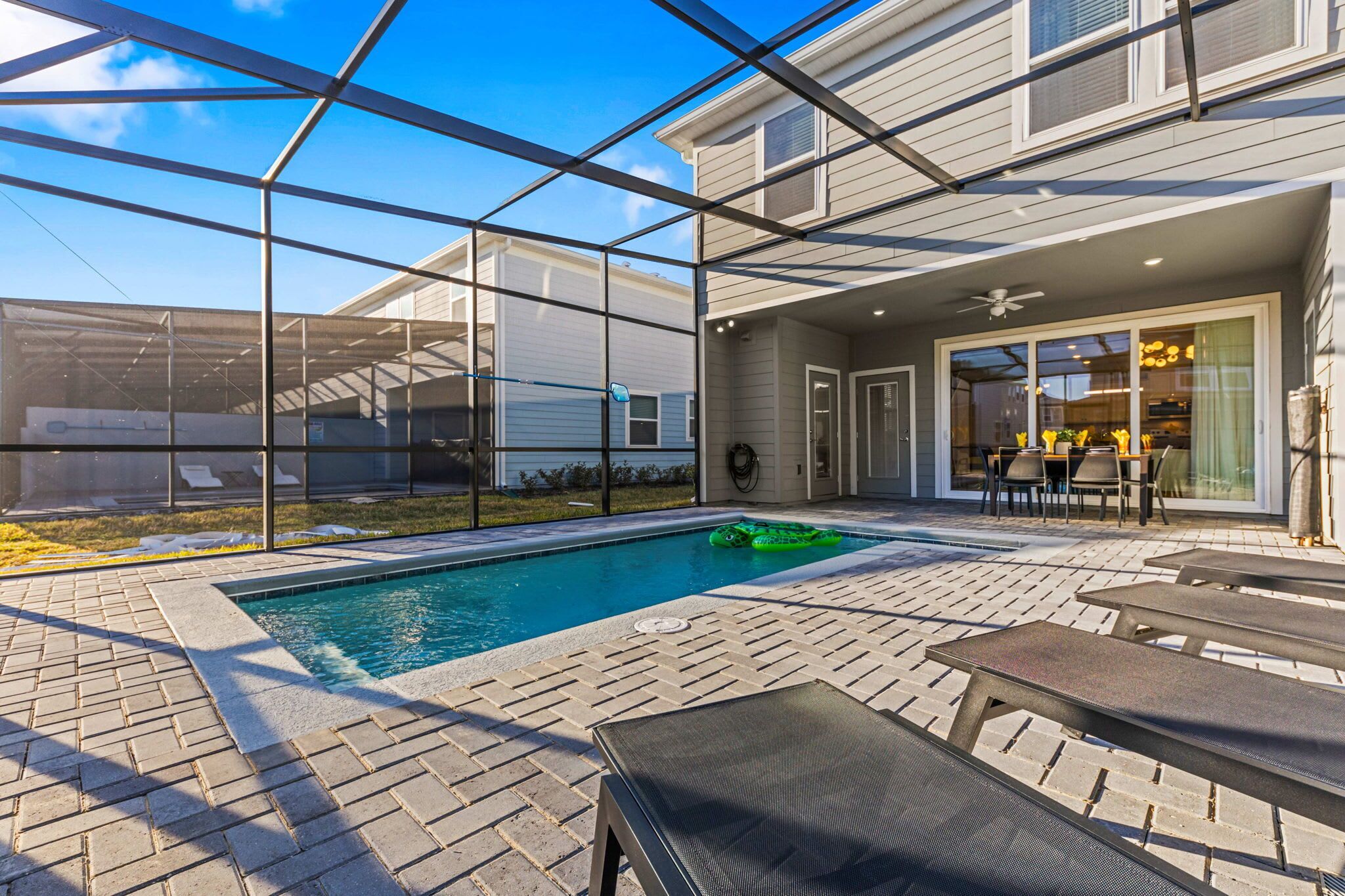 Un jardin avec une piscine, des chaises longues et un patio couvert.
