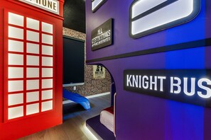 A room with a red telephone booth, a sign reading "ALL DESTINATIONS (NOTHING UNDERWATER)", and a "KNIGHT BUS" sign. - 5BR w Pool Grill Game Lounge Indoor Slide 16165 (Clermont)
