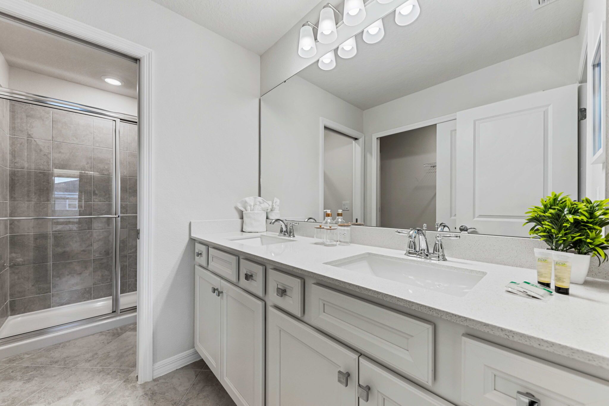 Un baño moderno con dos lavabos, un espejo grande y una cabina de ducha.