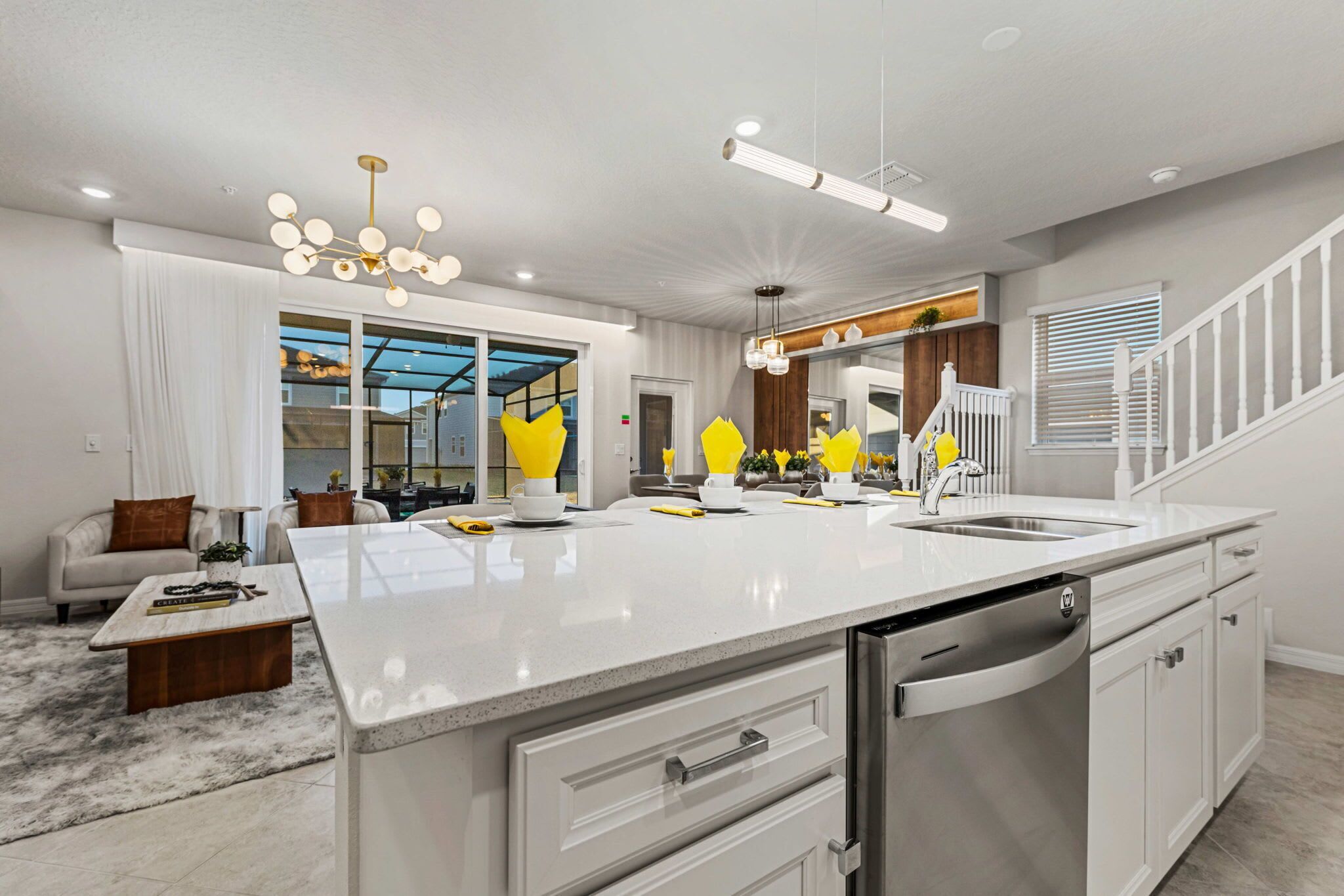 A modern kitchen with a large island, white cabinetry, and a stainless steel dishwasher.