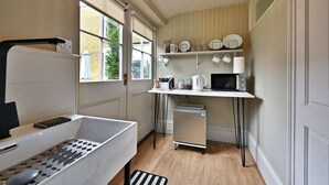 Una cocina compacta con ventana, una encimera blanca, un refrigerador pequeño y un microondas.