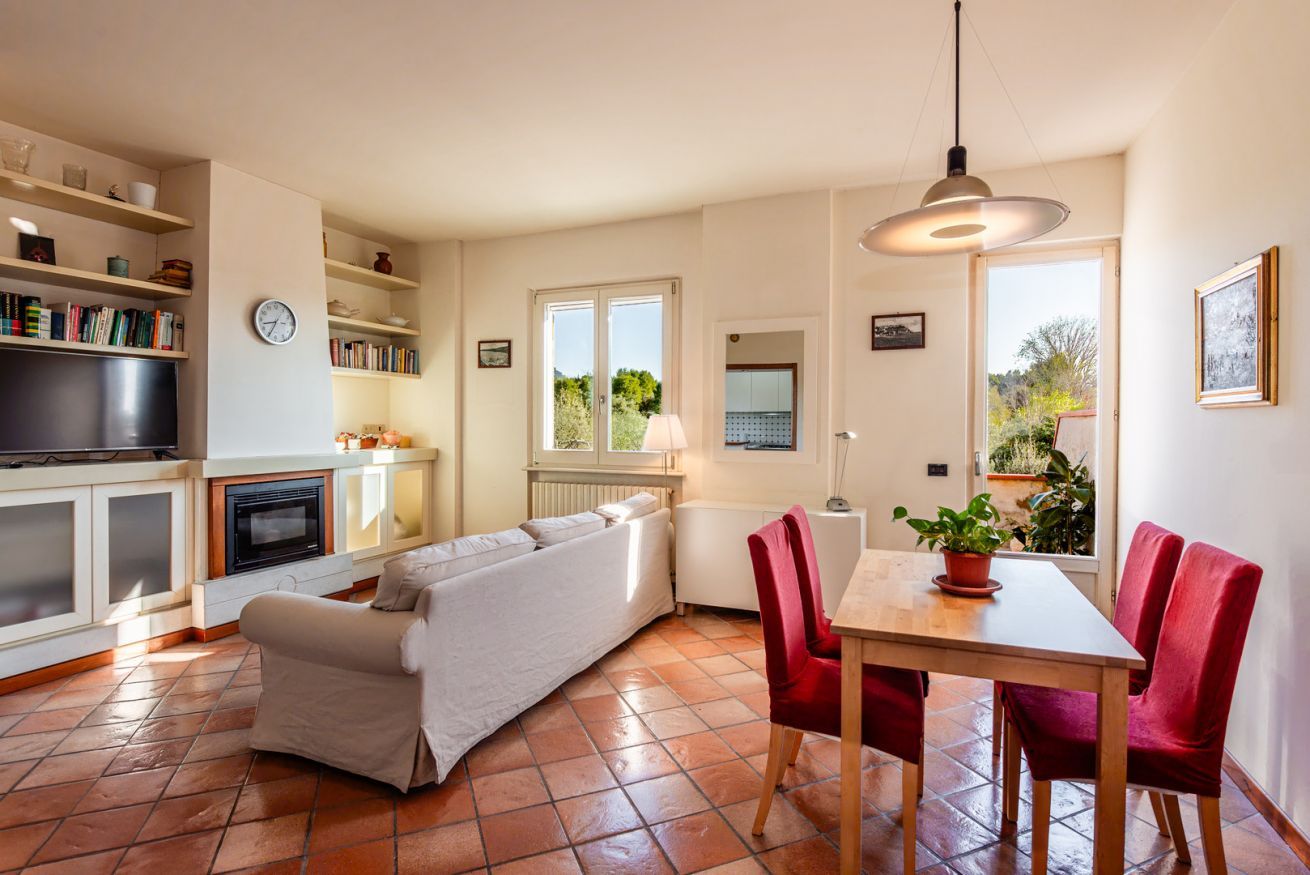 A cozy living room with a sofa, a dining table with chairs, a TV, and shelves with books and decorative items.