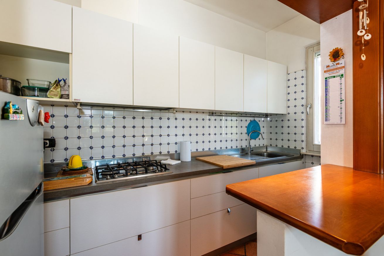A kitchen with white cabinets, a tiled backsplash, a gas stove, and a wooden countertop.