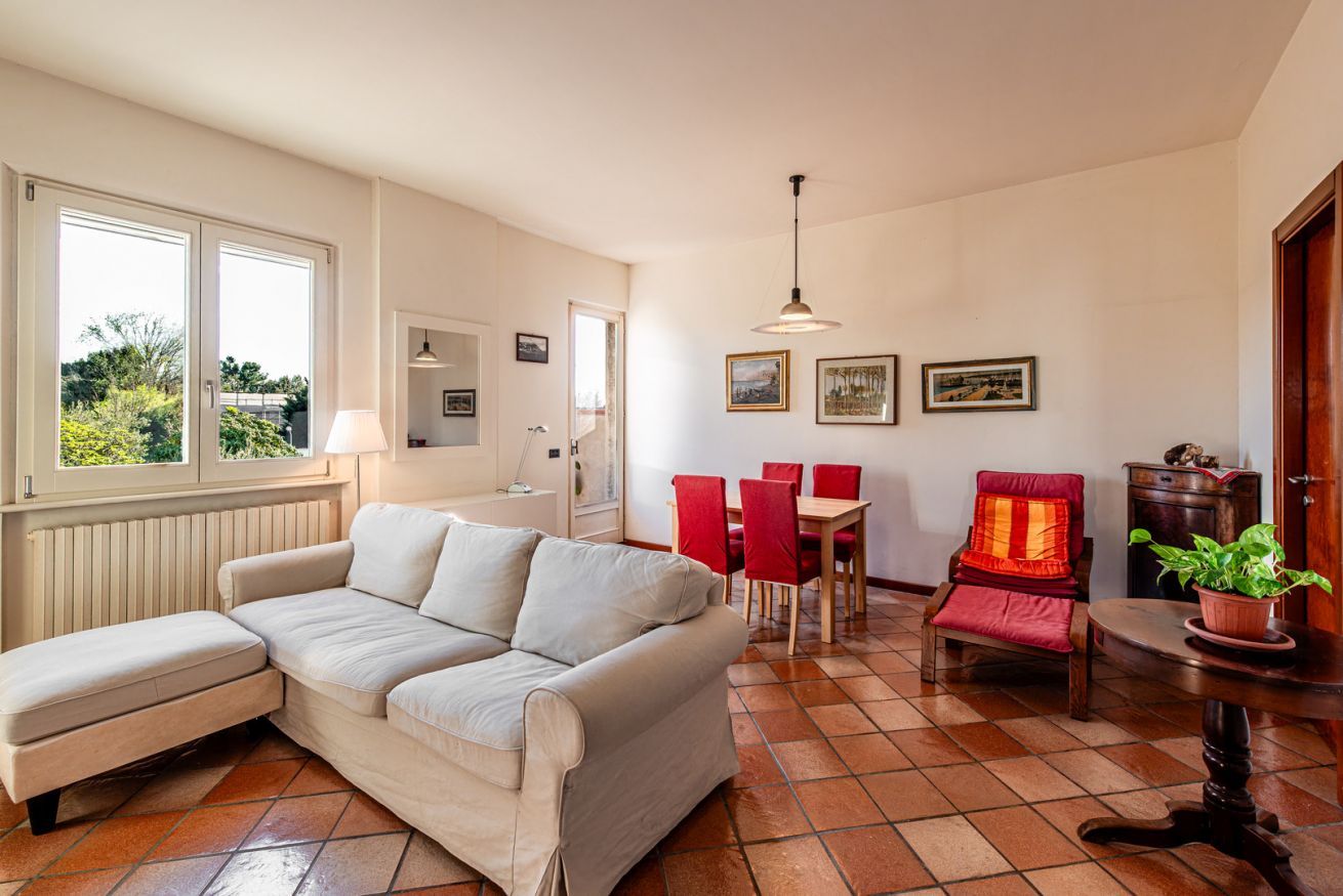 A living room with a sofa, red chairs, a dining table, and a potted plant.
