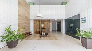 A modern lobby with a wooden bench, potted plants, and a glass door leading to a room. - Building w/ Pool Just 700m fr/ Ponta Verde Beach - Mbrs (Maceió)