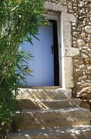 Un edificio de piedra con una puerta azul y una escalinata de piedra que conduce a él.